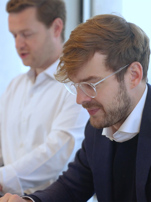 Video still image of men working on laptops